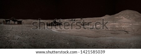 Panoramic night view of a group of two Berber tents mounted in the Sahara desert in Morocco, Africa. The starry sky illuminated the deserted mountains and the sand dunes.