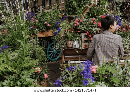 Woman playing piano decorated with flowers at Covent Garden, London. Rear view.
