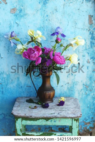 bouquet of peonies and irises in vintage  vase on rustic background