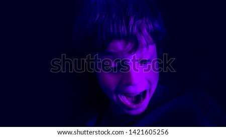 Cute boy laughing and squealing  in darkness playing exciting game