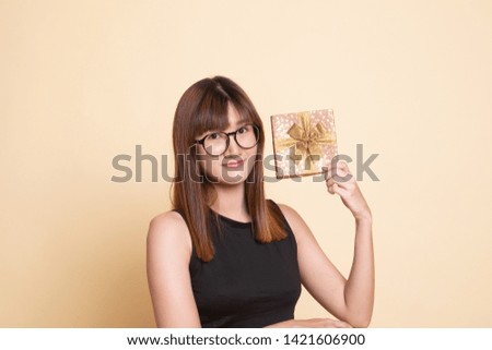 Young Asian woman with a gift box  on beige background