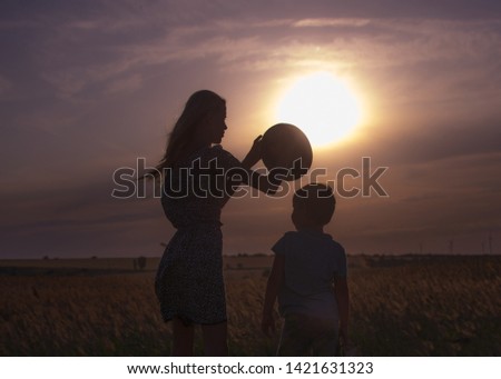 brother and sister opposite the setting sun in a field in summer