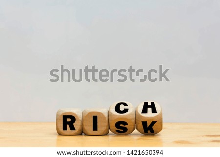 Wood cube word risk or rich on wooden table white background. 
Stock market need to risk it rich Concept. 