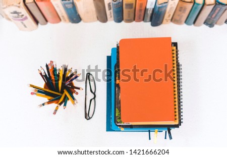 Notebooks piles, stack of books education back to school background, textbooks, glasses and pencils in plastic holder with copy space for text, top view