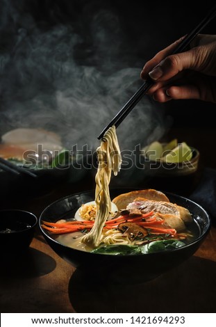 Hand with chopsticks takes noodles of ramen soup. Traditional Asian cuisine. Royalty-Free Stock Photo #1421694293