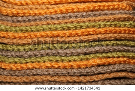 A pile of bright orange, brown and green knitted elements. Warm and soft background, wallpaper, pattern