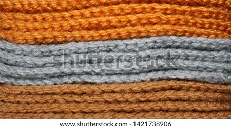 A pile of bright orange, gray and brown knitted elements. Warm and soft background, wallpaper, pattern