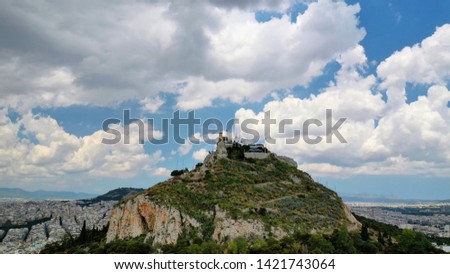Aerial panoramic photo of famous Lycabettus hill with iconic chapel of Saint George on top and beautiful clouds,Athens, Attica, Greece