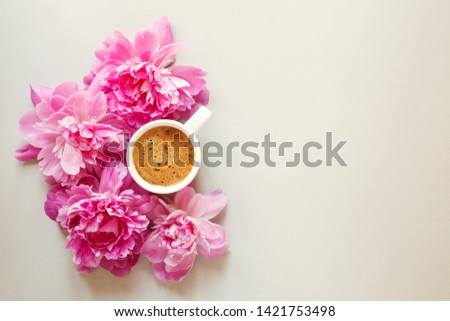 morning cup of coffee and fresh beautiful spring pink peony flowers on light background, top view, flat layout, copy space