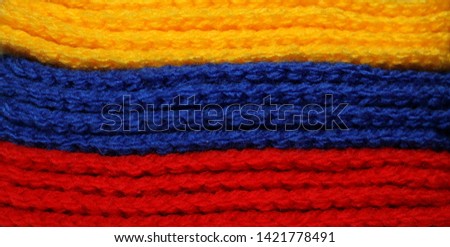 A pile of bright yellow, blue and red knitted elements. Warm and soft background, wallpaper, pattern