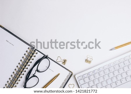 Fashion blog hero. Flat lay home office desk. Female workspace with computer keyboard, golden accessories, glasses, black diary on white background. Top view feminine background.