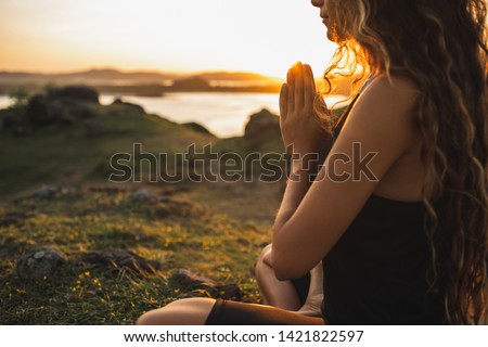 Woman praying alone at sunrise. Nature background. Spiritual and emotional concept. Sensitivity to nature.