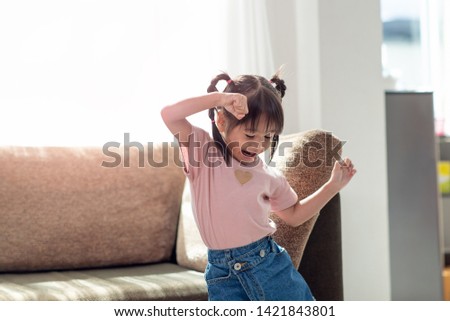 Happy Asian child having fun and dancing in a room, active leisure and lifestyle concept