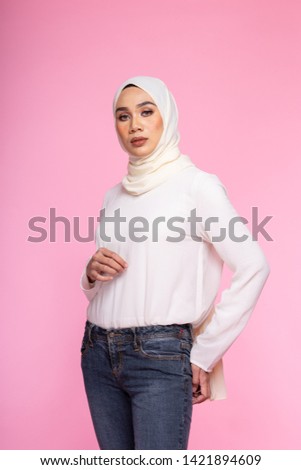 Portrait of a beautiful Muslim female model wearing sweatshirt with hijab  isolated over pink background. Studio fashion and beauty concept.