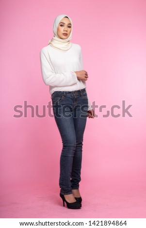 Portrait of a beautiful Muslim female model wearing sweatshirt with hijab  isolated over pink background. Studio fashion and beauty concept.