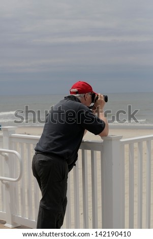 man in red hat and black clothes, taking pictures of beach in Cape May New Jersey