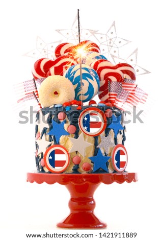 USA theme on-trend candyland fantasy drip cake with lollipops and candy decorations on white background.