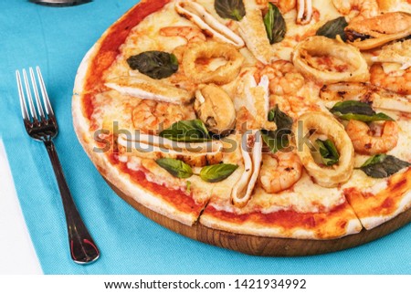 
European cuisine, Italian cuisine, Mediterranean dish. Sea Pizza from assorted fish, Colmar rings, greens and tomato sauce