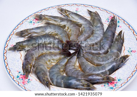 Raw shrimp arranged on a plate in a circle On a white plate on a white background