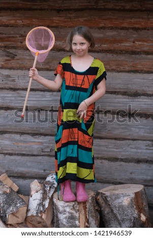 little country girl posing near a wooden house, standing in a colored dress