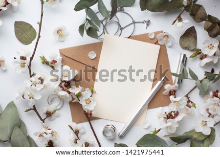 card mockup with cherry branch, flower, craft envelope, blossom and 
eucalyptus. craft resycling envelope, flat lay, top view