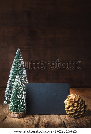 Merry Christmas and happy new year on blackboard with xmas tree and gold pine cone on grunge wood table and dark brown wooden wall.winter holiday greeting card