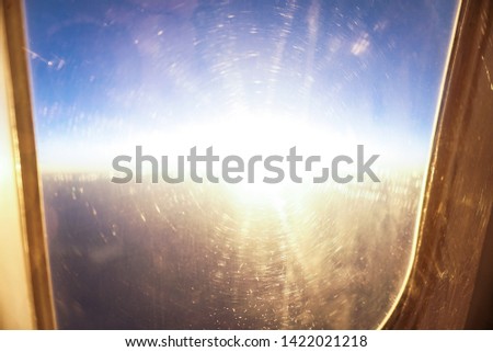 Airplane window with a sunset view. Sunrise in flight on vacation. Theme of tourism for the travel agency. Stock photo