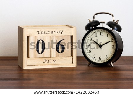 Wood calendar with date and old clock. Thursday 6 July
