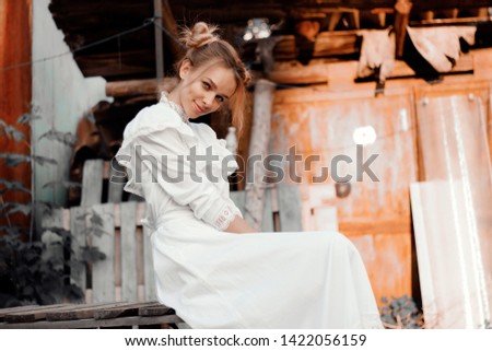 young girl in retro style in white dress sitting smiling emotion of joy in the village