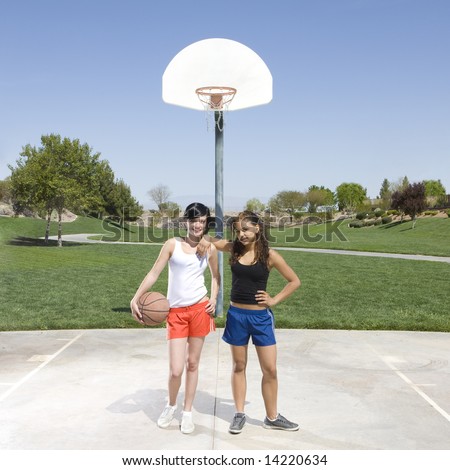 Two teen girls hang out at a basketball court in a park