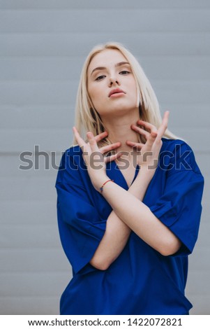 A stylish young girl, a doctor or a nurse poses for the advertising photography of a medical shirt for medical staff, comfortable and stylish clothes. Street photography