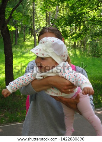 Young woman playing with a baby in the Park in her arms. the surprised look of the child.