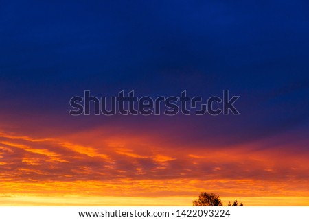 Colorful dramatic sky at sunset with layered rain clouds of bright blue and orange. A beautiful picture can be associated with the sea and lava.