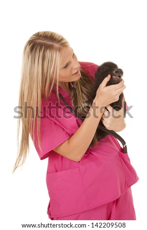 a woman vet in her pink scrubs holding on to a pig looking in it's mouth.
