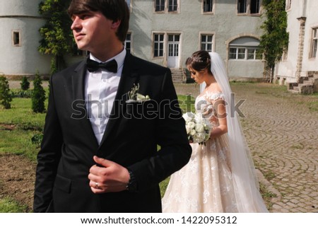 Newlyweds stand in front of castle. Groom and bride