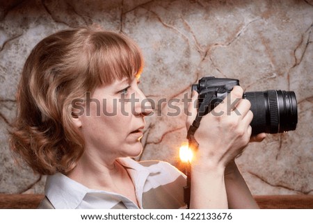 Blonde-haired female photographer with photo camera in her hands. Woman taking a photo