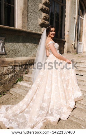 Beautiful bride in elegant wedding gress go up the stairs. Big train drees