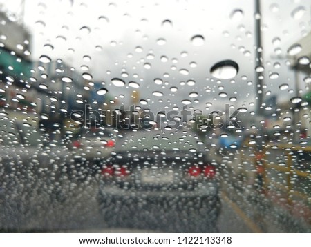 Soft light texture from rain droplet on car glass with blurred car background.Sky and rain clouds with traffic jams background.