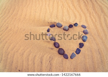 Heart made of pebbles in the sand. Beach background. Top view with copy space.