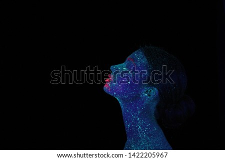 Profile of an alien woman with blue skin and pink lips, ultraviolet makeup on a black background. Head up. Star system on the skin.
