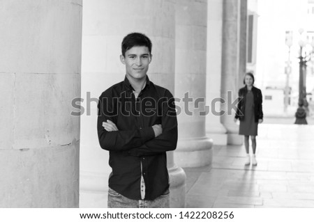 Slim, handsome, smiling sporty man went on a date and waits for his beloved woman on the street. Black and white photography outdoors portrait