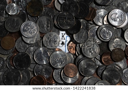 King playing card under a pile of coins