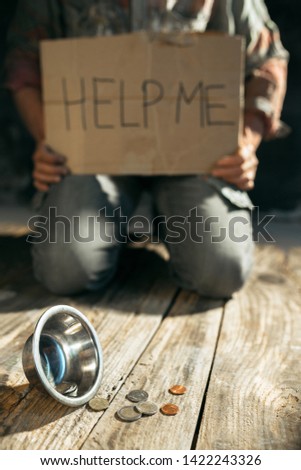 Male beggar hands seeking money with sign HELP ME from human kindness on the wooden floor at public path way or street walkway. Homeless poor in the city. Problems with finance, place of residence.