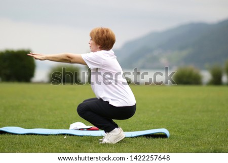 Woman doing fitness on green grass.