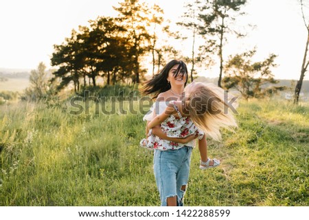 Mother and daughter having fun in the park. Happiness and harmony in family life. Beauty nature scene with family outdoor lifestyle.