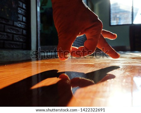 Hand and shadow of the hand from the light on the floor