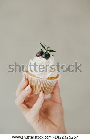Girl holding cupcake with berries in hand.
