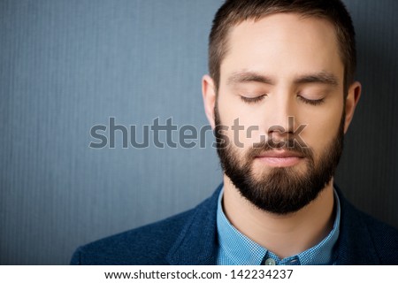 Closeup of handsome businessman with eyes closed against blue background Royalty-Free Stock Photo #142234237