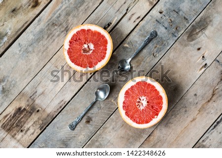 close-up of fruit. Two halves of red ripe grapefruit with teaspoons lie on an old stylized wooden background trendy flatlay. stylish food photography. creative phone image. Copy spase