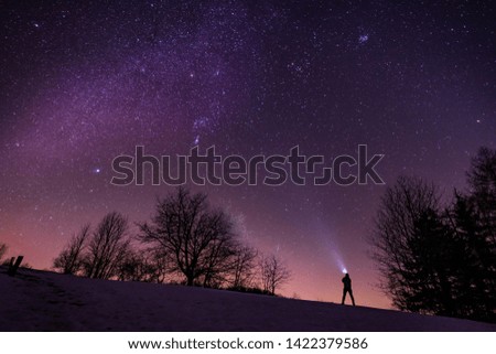 A man watching the Milky Way with a headlight on. Adventurous photo of a starry night. Stars on the sky and a man watching them.